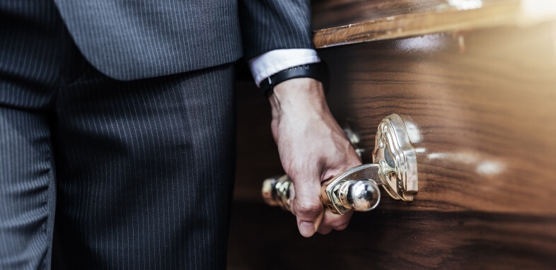 Wrongful-Death close up of man in suit holding casket handle