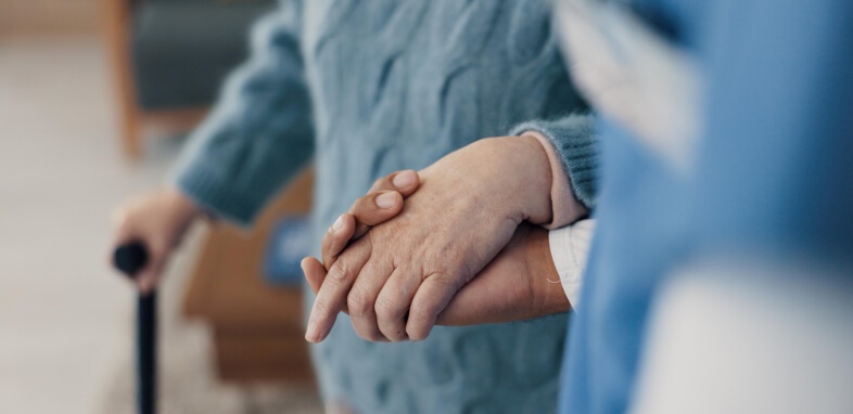 Nursing-Home-Abuse close up of elderly person holding hands with caretaker